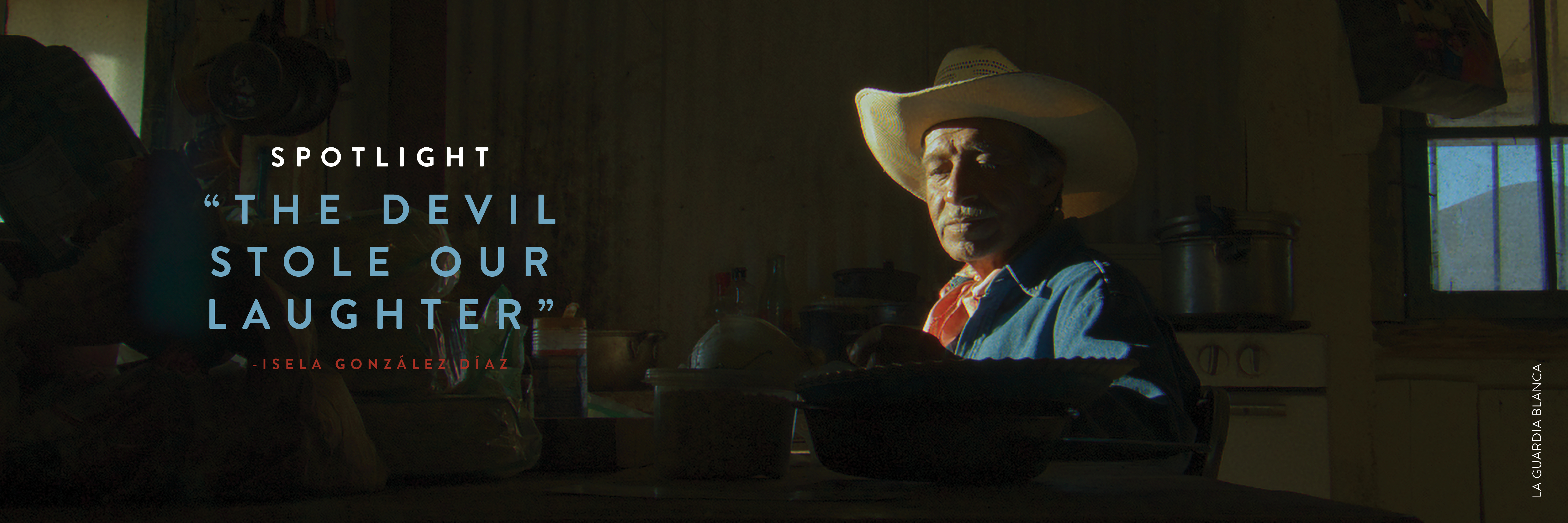 A man sits in a darkly lit kitchen with sunshine on his face and shoulders, wearing a denim shirt, red kerchief around his neck and a cowboy hat. Text in white, blue and red overlays the image and reads: Spotlight THE DEVIL STOLE OUR LAUGHTER -Isela González Díaz